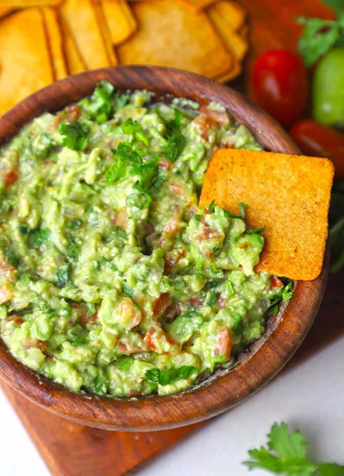 aerial shot of guacamole served in a wooden bowl with chips.