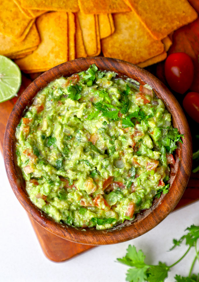 aerial shot of guacamole served in a wooden bowl with chips.