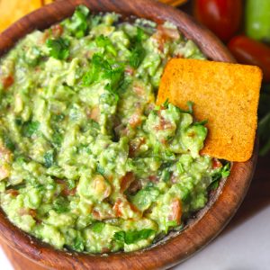 aerial close up shot of guacamole in a wooden bowl.
