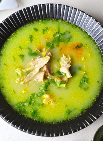 aerial shot of chicken shorba in a black ceramic bowl.
