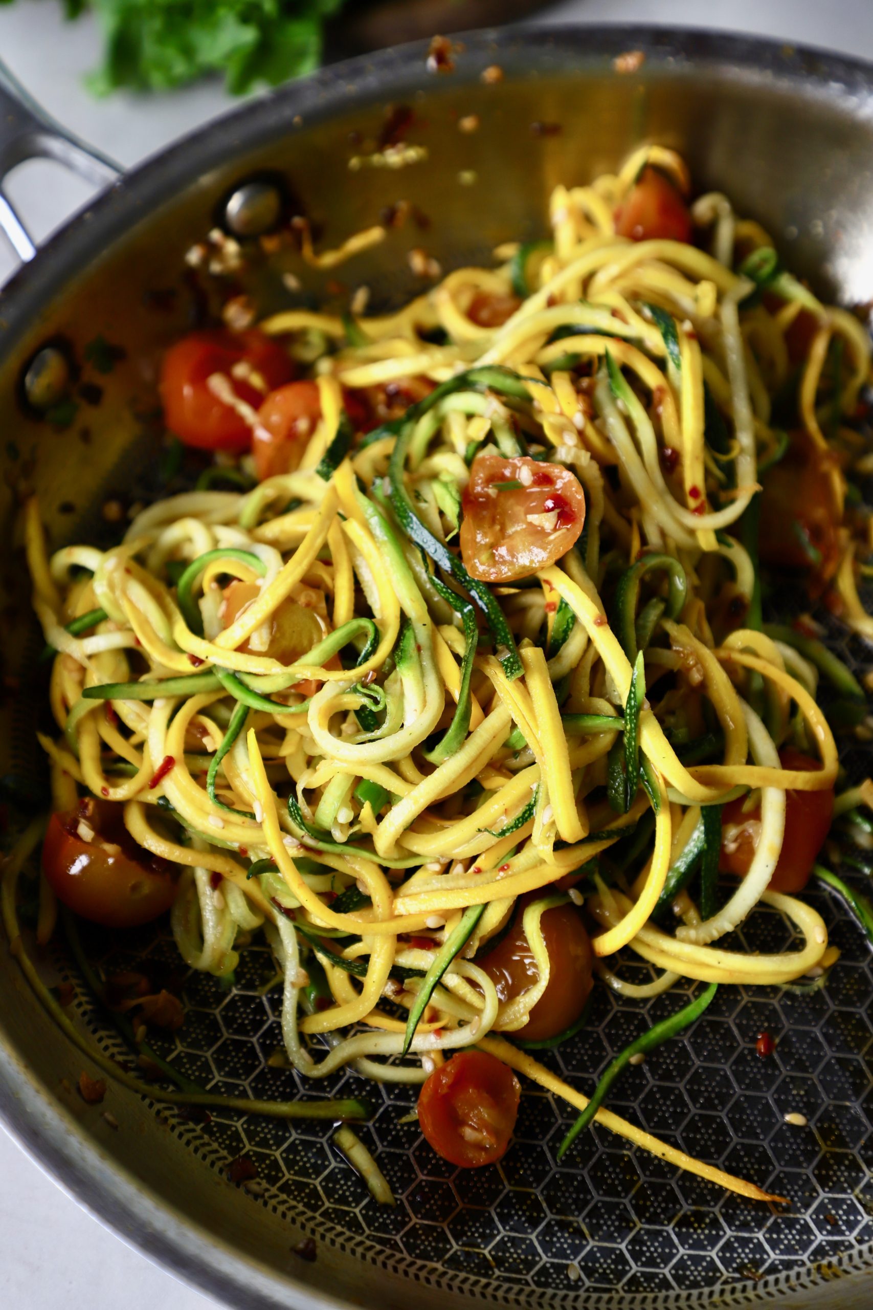 side close up shot of zucchini noodles in a pan.