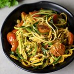 side close up shot of zucchini noodles in a black bowl.