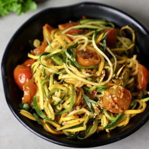 side close up shot of zucchini noodles in a black bowl.