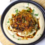 aerial shot of cabbage steak served on a bed of hummus.