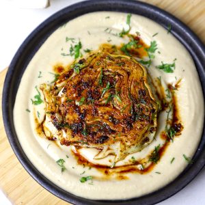 aerial shot of cabbage steak served on a bed of hummus.