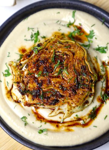 aerial shot of cabbage steak served on a bed of hummus.
