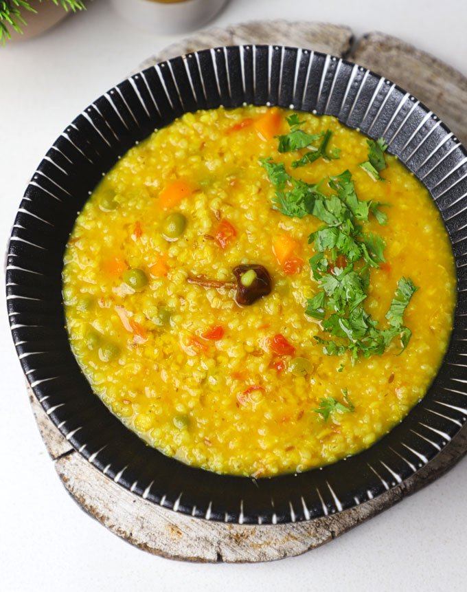 aerial shot of barley khichdi in a black bowl.