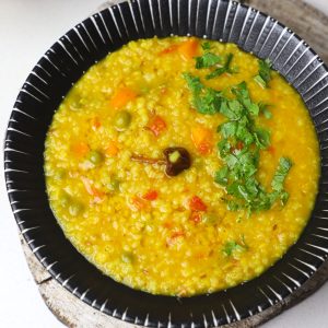 aerial shot of barley khichdi in a black serving bowl.
