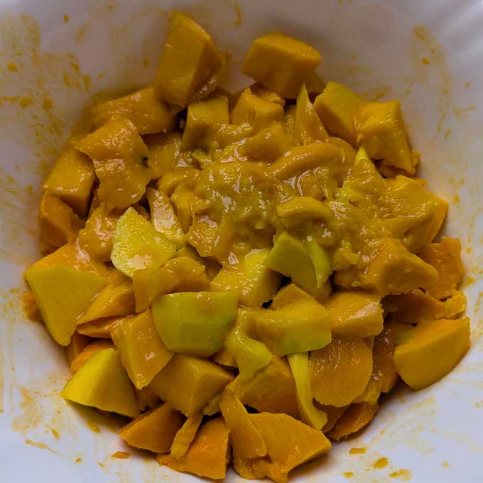 mixing diced mango with sugar.