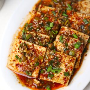 side close up shot of braised tofu served in a white platter.