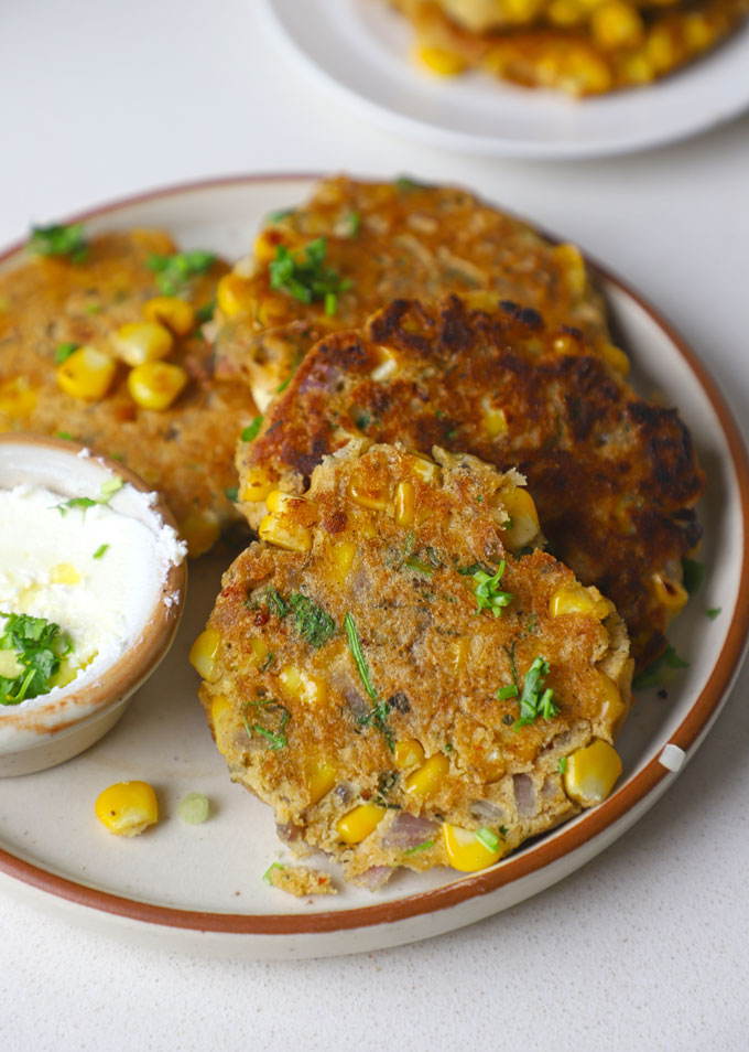 side close up shot of gluten free corn fritters served on a platter with dip.