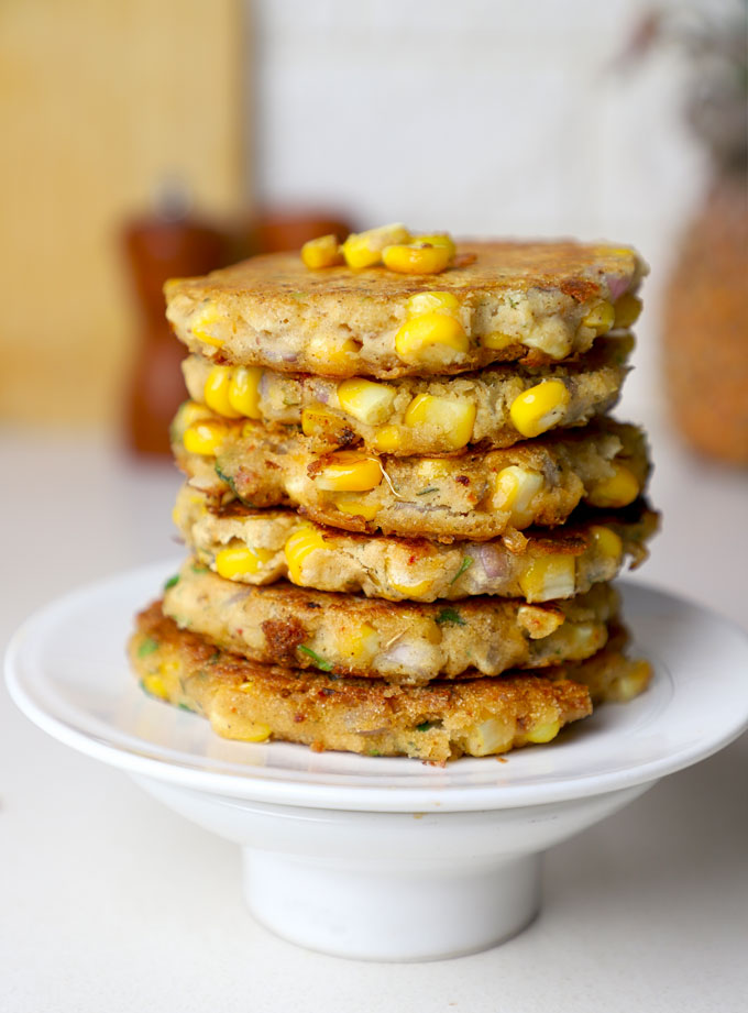 side close up shot of gluten free corn fritters stacked on a white plate.
