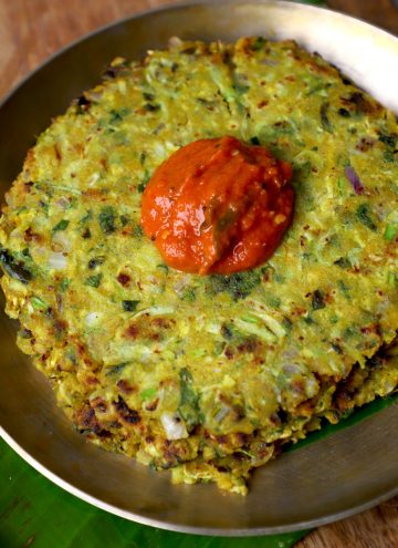 side close up shot of jowar thalipeeth served with chutney in a kansa plate.