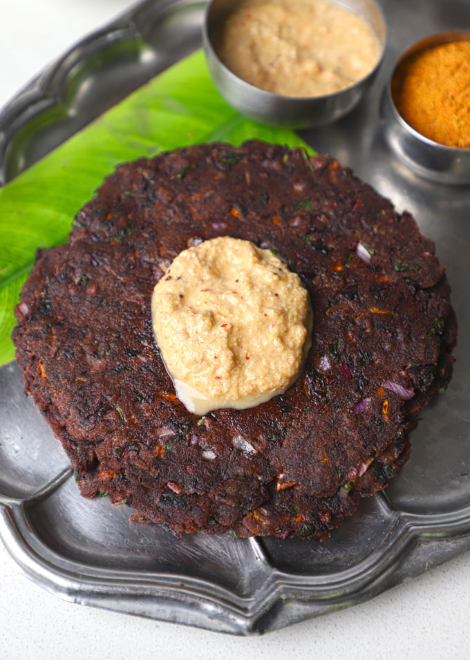 aerial shot of ragi adai topped with chutney on a stainless steel platter.