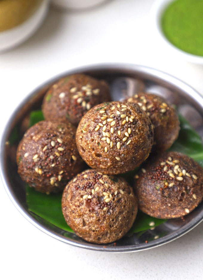 side close up shot of ragi appe stacked on a stainless steel platter.