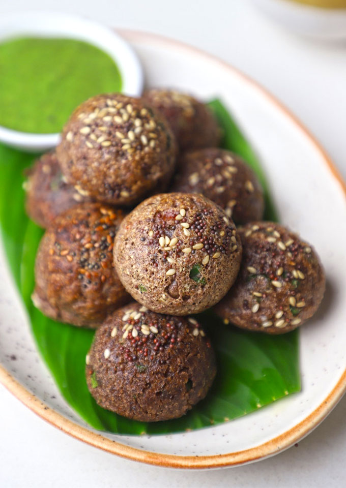 aerial shot of ragi appe served in a platter with green chutney.